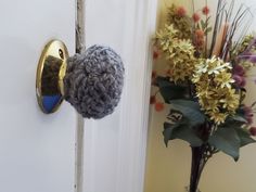 a close up of a door handle on a white door with flowers in the background