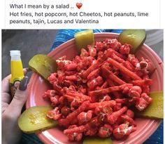 a pink plate topped with cucumbers and pickles next to a bottle of orange juice