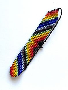 a multicolored beaded tie on a white surface with a black string attached to it