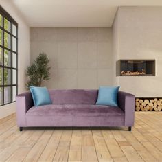 a purple couch sitting in front of a window on top of a hard wood floor