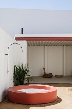 an outdoor hot tub in front of a white building with a red awning over it