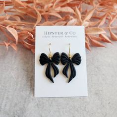 These black bow dangle earrings are super lightweight and a great statement accessory. These earrings are handmade out of black polymer clay in small batches. Dimensions: Length: approximately 2 inch Width (at widest point): approximately 1 inch Materials Polymer clay Gold-finished stainless steel fish hook Resin PLEASE NOTE Each earring is handmade and so dimensions may differ slightly. Colors may differ based on computer settings. Super Clay Earrings, Bow Clay Earrings, Air Dry Clay Jewelry, Polymer Clay Designs, Clay Earrings Black, Black Polymer Clay, Clay Inspo, Clay Dangle Earrings, Tag Ideas