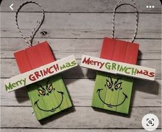 two christmas decorations made out of popsicle sticks with the grin face on them, hanging from twine strings