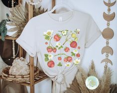 Strawberry Shirt, Strawberry Clothes, Strawberry Top, Garden Shirt, Aesthetic Clothing, Cottagecore Clothes, Cottage Core, Botanical Shirt, Strawberry Print, Gardening Shirts, Gardener Gifts, Summer Berry Tee, Floral Graphic Tee Get ready, this shirt is about to become your favorite! Made of super soft cotton with a comfy fit, you'll find it fits in with all your outfits! The details: Super Soft Pre-shrunk Cotton Tee Unisex - Fits true to size (see size chart for references of length and width) Summer Cottagecore Shirt With Relaxed Fit, Cottagecore Relaxed Fit Summer Shirt, White Strawberry Print Shirt For Spring, Relaxed Fit Cottagecore Summer Shirt, White Cottagecore Top With Plant Prints, Summer Cottagecore Relaxed Fit Shirt, White Cottagecore Tops With Plant Print, Cotton Shirt With Strawberry Print For Spring, White Cottagecore T-shirt For Summer