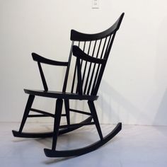 a black rocking chair against a white wall