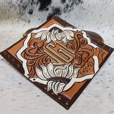 a brown and white cowhide with an ornate design on the inside of its leather wallet