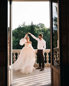 a man and woman standing in front of an open door with their arms outstretched to each other