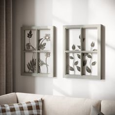 a living room filled with furniture and two framed pictures on the wall next to a window