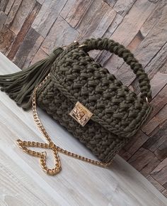 a crocheted bag with a tasseled handle on a wooden table next to a wall