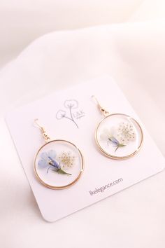 These lovely earrings are made from multiple layers of resin, Forget Me Not flowers, and Queen Ann's Lace flowers.Since real flowers are used for this piece, please note that there will be some variations in the flowers and branches. However, this is what makes each piece unique and one of a kind. Size: About 1.5" (2" with hooks) Cheap Pressed Flowers Earrings, Cheap Pressed Flower Earrings, Cherry Blossom Earrings Pressed Flower, Forget Me Not Resin Earrings, Pressed Flower Earrings, Forget Me Not Flowers, Lovely Earrings, Clear Resin, Pressed Flower