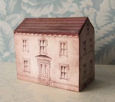 a small toy house sitting on top of a table next to a blue floral wallpaper