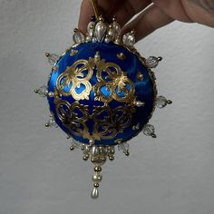 a hand holding an ornament that is blue and gold