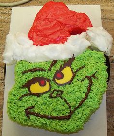 a cupcake with green frosting and a red santa hat on it's head