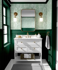 a bathroom with black and white wallpaper, green cabinetry, gold fixtures and a blue rug