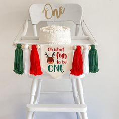 a birthday cake sitting on top of a white chair with tassels around it