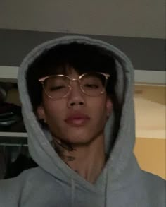 a young man wearing glasses and a hoodie