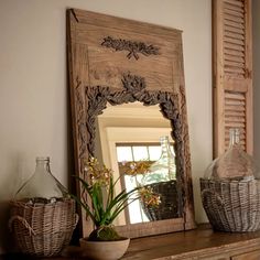 a mirror sitting on top of a wooden dresser next to a vase and basket filled with flowers