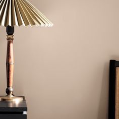 a table lamp sitting on top of a wooden stand next to a wall mounted clock