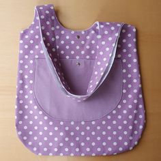 a purple and white polka dot bag sitting on top of a wooden table