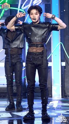 two men in leather outfits on stage with one holding his hands up to the side