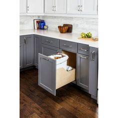 a kitchen with gray cabinets and white counter tops, an open cabinet drawer in the middle