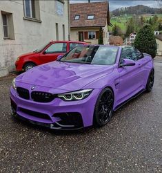 a purple bmw is parked in front of two red cars