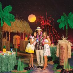 two women and a man are standing in front of a tiki hut at night