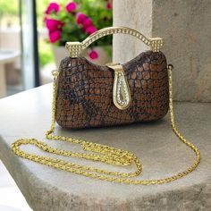 A stunning miniature brown faux alligator clutch with a gold tone crossbody chain and hardware. It features rhinestone studded hardware with a snap closure. The lining is made of soft black fabric. The handle drop is about 1 1/2" and the crossbody chain drop is 20". The bag measures approximately 2 3/4" high, 4 7/8" wide and 1 3/4" deep. It's in very nice condition, clean and odor free. There are no stains and it's not missing any rhinestones. Rhinestone Studs, Soft Black, Black Fabric, Alligator, Snap Closure, Evening Bags, Bags Handbags, Gold Tones, Shoe Accessories