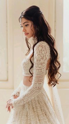 a woman in a white wedding dress with long sleeves