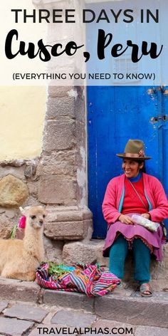 a woman sitting in front of a blue door next to a llama