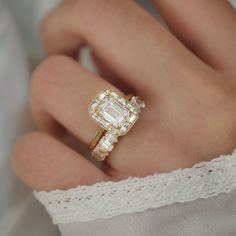 a close up of a person's hand wearing a ring with an emerald stone