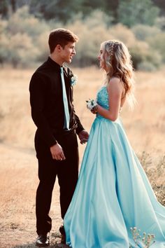 a young man and woman dressed in formal wear looking at each other while standing next to each other