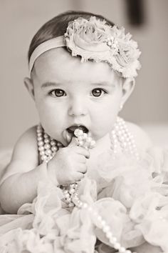 black and white photo of a baby wearing pearls