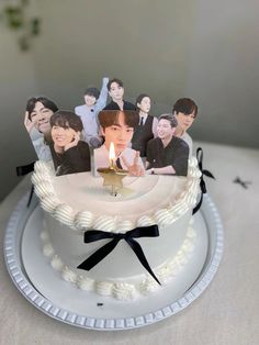 a white cake topped with pictures of people and a lit candle on top of it