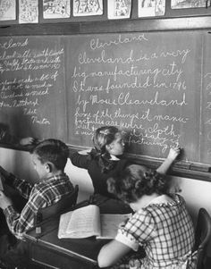 three children are writing on a chalkboard in front of a blackboard with many letters