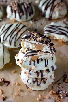 several desserts are stacked on top of each other with chocolate drizzle and nuts