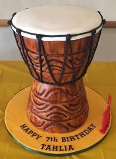 a birthday cake made to look like a drum on a yellow tablecloth with the words happy 7th birthday tahla