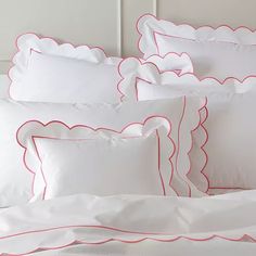 a bed with white sheets and red trimmings on the pillowcase is shown