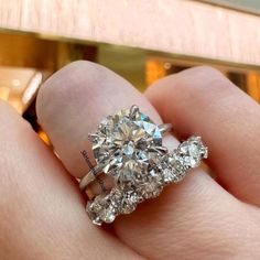 a woman's hand holding an engagement ring with three stone diamonds on the band