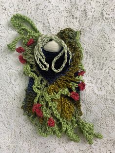 a crocheted scarf is laying on a lace tablecloth, with a hat in the center