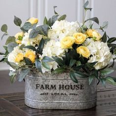 a metal bucket filled with yellow and white flowers