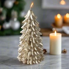 a small gold christmas tree sitting on top of a table next to a lit candle