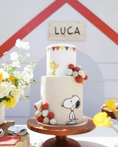 a white and red cake sitting on top of a wooden table next to yellow flowers