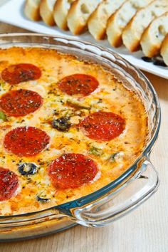 a pepperoni and cheese pizza in a glass dish with slices of bread on the side