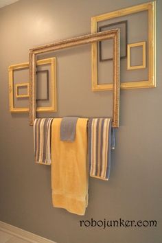 a towel rack is hanging on the wall in front of a mirror and two framed pictures