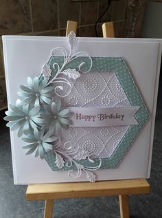 a happy birthday card with flowers and ribbon on the front, sitting on a easel