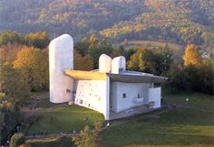 an aerial view of a large white building in the middle of a field with trees around it