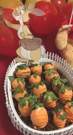 a bowl filled with chocolate covered strawberries on top of a table next to balloons