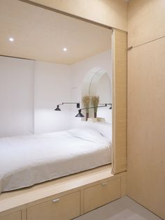 a bed sitting under a mirror next to a wooden shelf filled with drawers and lights