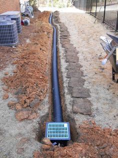 a drain that is in the ground next to a fence